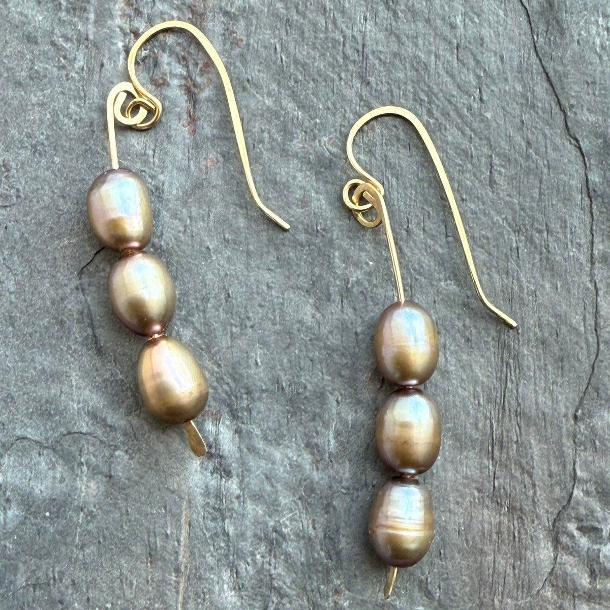 Pair of pearl earrings on a textured gray surface